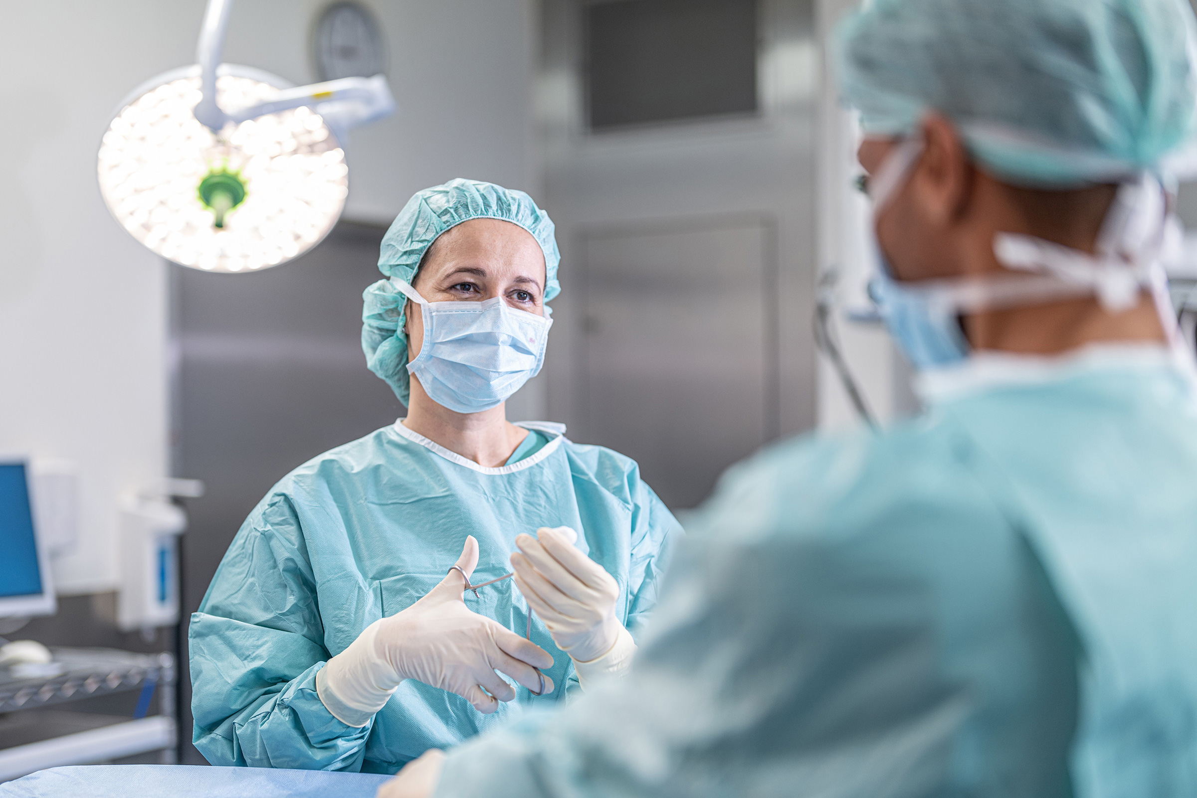 Zwei Ärzte stehen mit OP-Besteck in der Hand im Operationssaal.